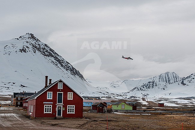 A plane flies above multicolored buildings and mountains at Ny-Alesund. Ny-Alesund, Kongsfjorden, Spitsbergen Island, Svalbard, Norway. stock-image by Agami/Sergio Pitamitz,